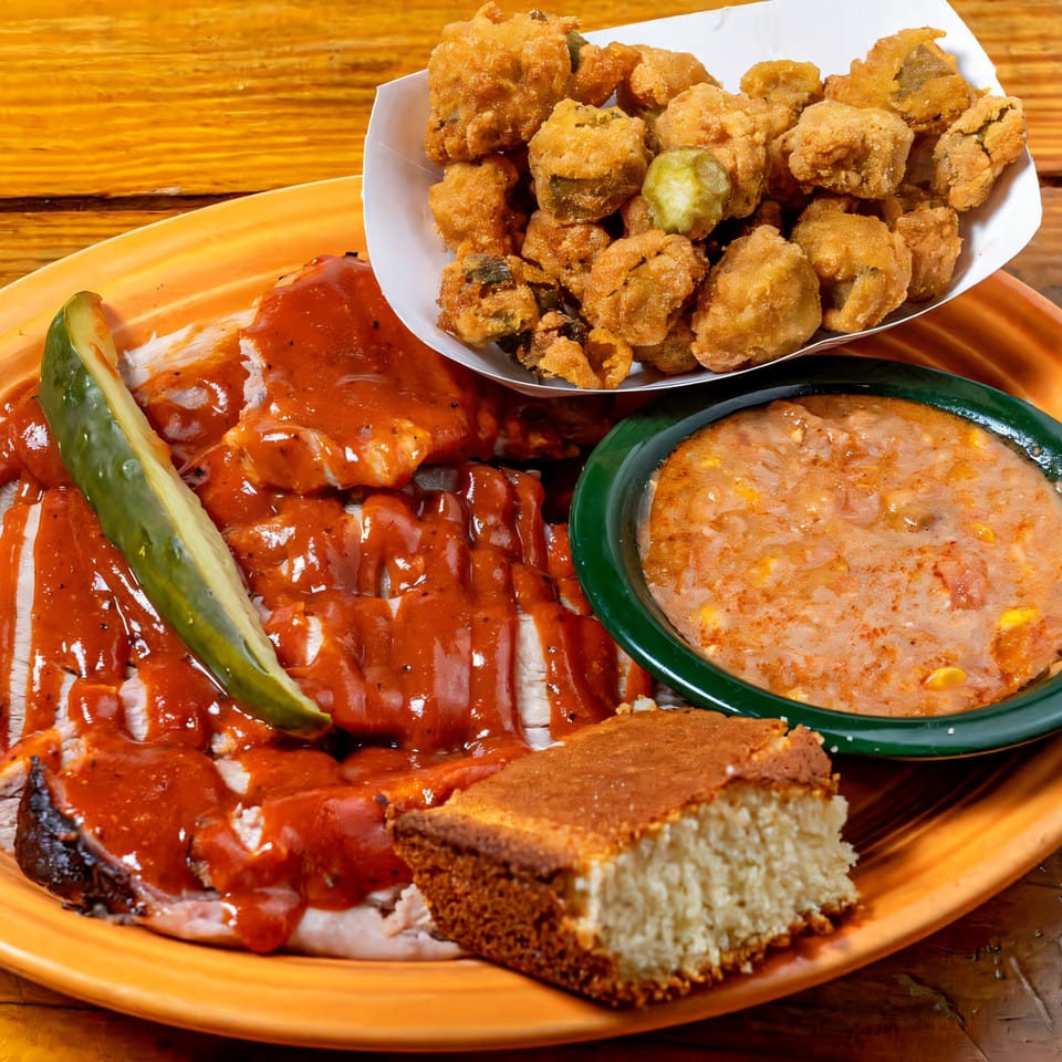 Big B Barbecue's sliced brisket with sauce, a pickle spear, fried okra, Brunswick stew, and cornbread.